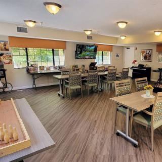 A comfortable dining area with tables, chairs, and a television.