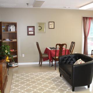 A cozy living room with a small dining area, featuring a bookshelf, couch, and carpet.