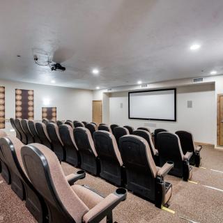 A cozy home theater with multiple rows of seating facing a large projection screen.