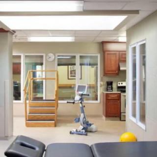 A rehabilitation therapy room with exercise equipment and a staircase.