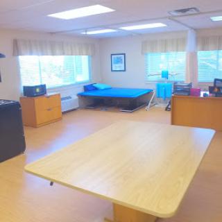 A spacious and well-lit room featuring a table, workspace, and rest area.
