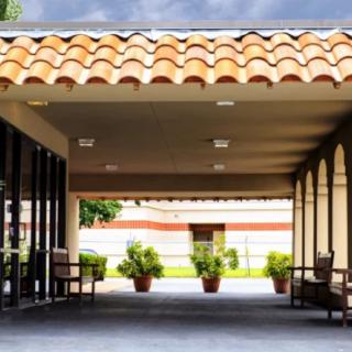 A covered walkway with a tiled roof and potted plants lining the entrance.