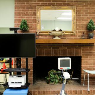 A cozy interior space featuring a television, a medical monitor, and decorative elements against a brick wall.