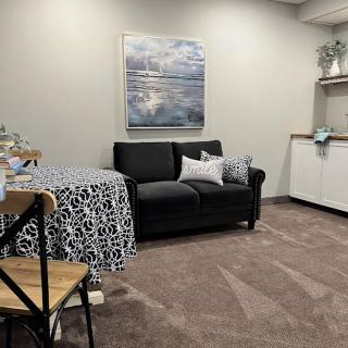 A cozy living room setup with a black sofa, decorative pillows, and a patterned tablecloth.