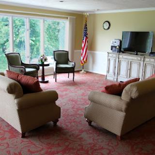 A cozy living room setup with comfortable seating, a television, and large windows letting in natural light.