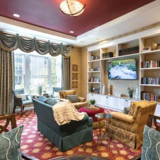 A cozy living room with elegant furnishings, bookshelves, and a large window allowing natural light.