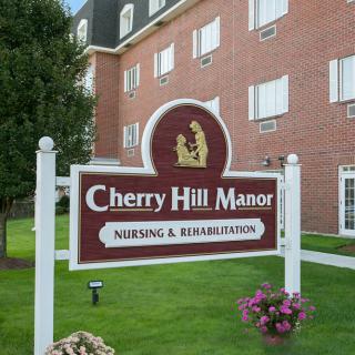 Sign for Cherry Hill Manor Nursing & Rehabilitation in front of a brick building with landscaped grounds.