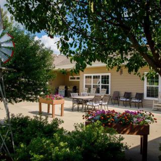 A sunny outdoor patio with garden furniture and colorful flowers.