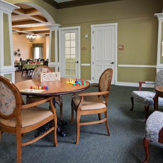 A cozy living area with a table and chairs, featuring a board game setup, leading into a dining room.