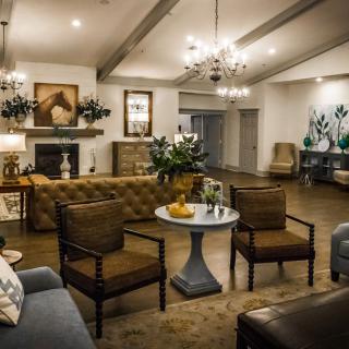 A cozy and elegantly decorated living room with a central seating area, featuring comfortable chairs, a round table, and a fireplace.