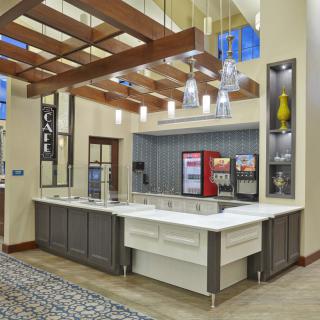 A modern cafe beverage station featuring sleek countertops and stylish hanging lights.