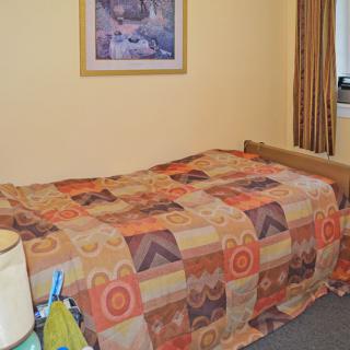 A cozy bedroom with a patterned blanket on a bed and wall art above.