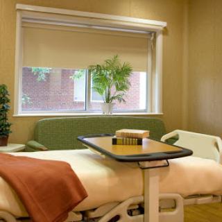 A cozy hospital room featuring a bed, a small table, and a window with a view.