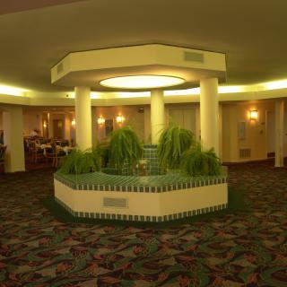 A hotel lobby with a central fountain surrounded by plants.