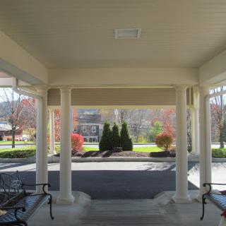 A serene entryway featuring decorative columns and benches, leading to a beautifully manicured garden.