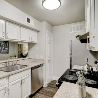 A modern kitchen with white cabinets and stainless steel appliances.