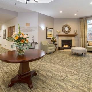 A cozy living room with a round table featuring a floral arrangement, comfortable chairs, and a fireplace.