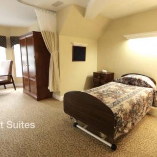 A cozy room with a hospital bed, wardrobe, and natural light from the window.