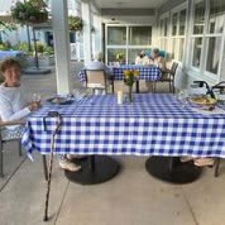 People enjoying a meal at an outdoor patio with a blue checkered tablecloth.