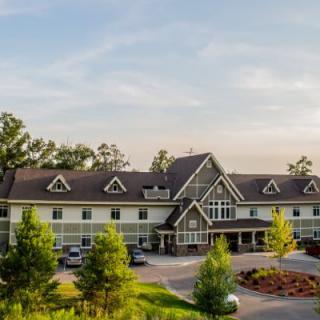 A large residential building surrounded by trees under a soft sky.