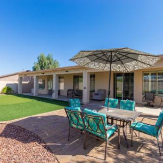 A serene outdoor patio setup with turquoise furniture and a shaded umbrella, perfect for enjoying sunny days.