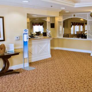 A hotel lobby featuring a reception desk and waiting area with carpeted flooring.