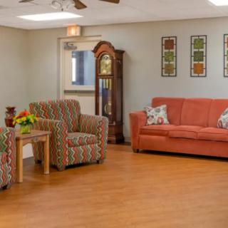 A cozy living room with a sofa, armchairs, and a grandfather clock.