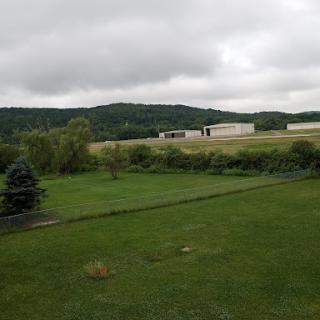 A serene landscape featuring an overcast sky, rolling hills, and expansive green fields.