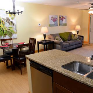 A modern apartment with a cozy living room and dining area, featuring stylish furniture and warm lighting.