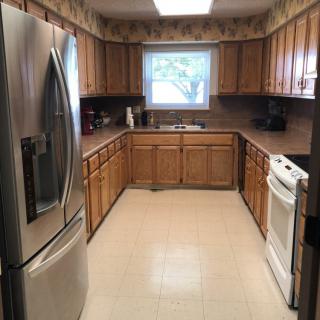 A kitchen with wooden cabinets, a refrigerator, and a stove.