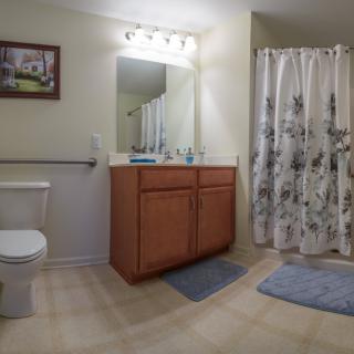 A clean and well-lit bathroom featuring a vanity with mirror, toilet, and shower area.