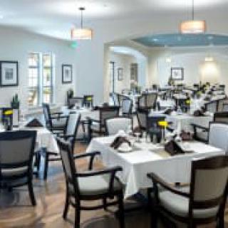 An elegant dining area with neatly arranged tables and chairs, featuring white tablecloths and stylish decor.