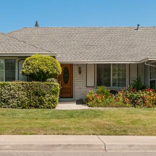 A charming suburban house with a well-kept lawn and neatly trimmed shrubs.