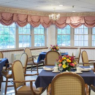 A well-arranged dining room with neatly set tables and decorative floral centerpieces.
