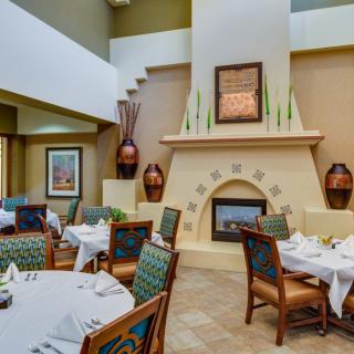 A cozy restaurant dining area with elegantly set tables and a decorative fireplace.