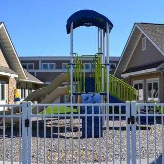 A fenced playground with a slide in a residential area.