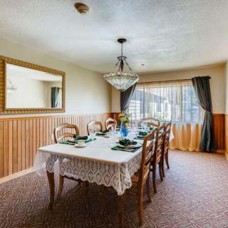 A well-decorated dining room with a large table set for a meal, featuring a chandelier and elegant curtains.