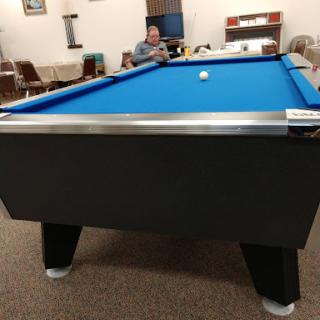 A pool table with a blue surface, set in a cozy game room.