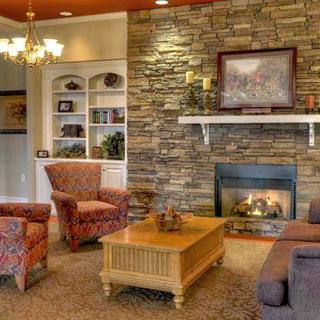 A cozy living room with a stone fireplace and comfortable seating.