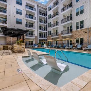 Modern apartment complex with an outdoor swimming pool and lounge area.