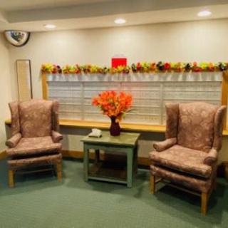 A cozy waiting area with two armchairs, a table adorned with a vibrant bouquet of flowers, and soft ambient lighting.