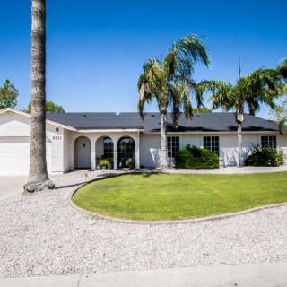 A suburban home with a neatly manicured lawn and palm trees in the front yard.