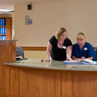Two medical staff members working at a hospital reception desk.