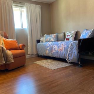 A cozy living room with a sofa, armchair, and window with curtains.