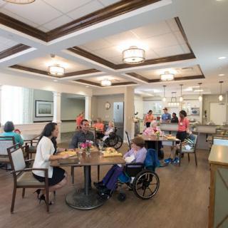 A communal dining area in a nursing home with residents and staff interacting.