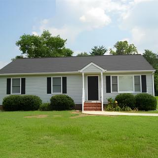 A single-story house with a well-maintained lawn and shrubbery.