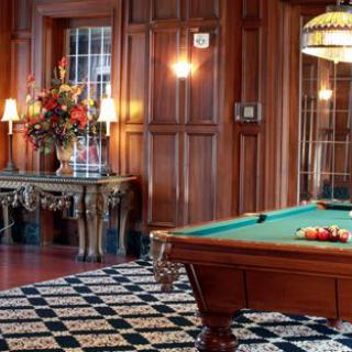 Luxurious billiard room with elegant wood paneling and a classic pool table.