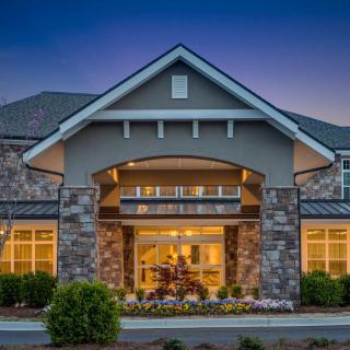 A beautifully lit residential building with stone accents and a welcoming entrance during the evening.