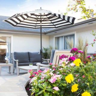 A cozy patio with comfortable seating and a striped umbrella, surrounded by vibrant flowers.
