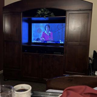 A television in an entertainment center displaying a program in a living room.